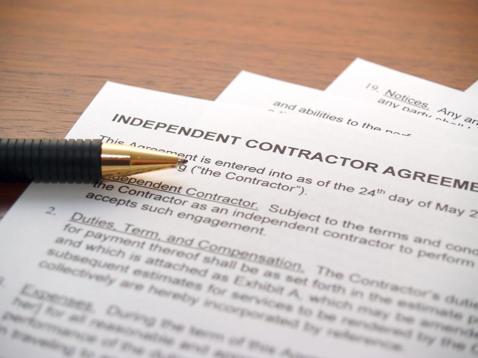 A close-up of an independent contractor agreement with a pen resting on top of the document.