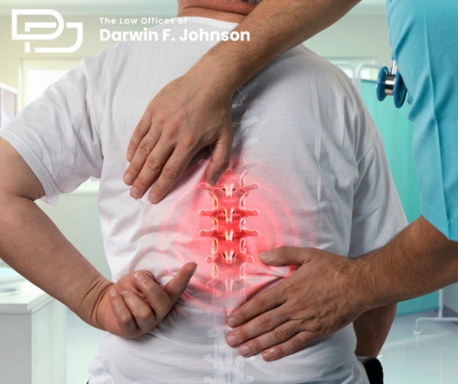 A doctor examines a patient’s lower back, highlighting the spine in red to indicate pain or injury. The Law Offices of Darwin F. Johnson logo is visible in the top left corner.
