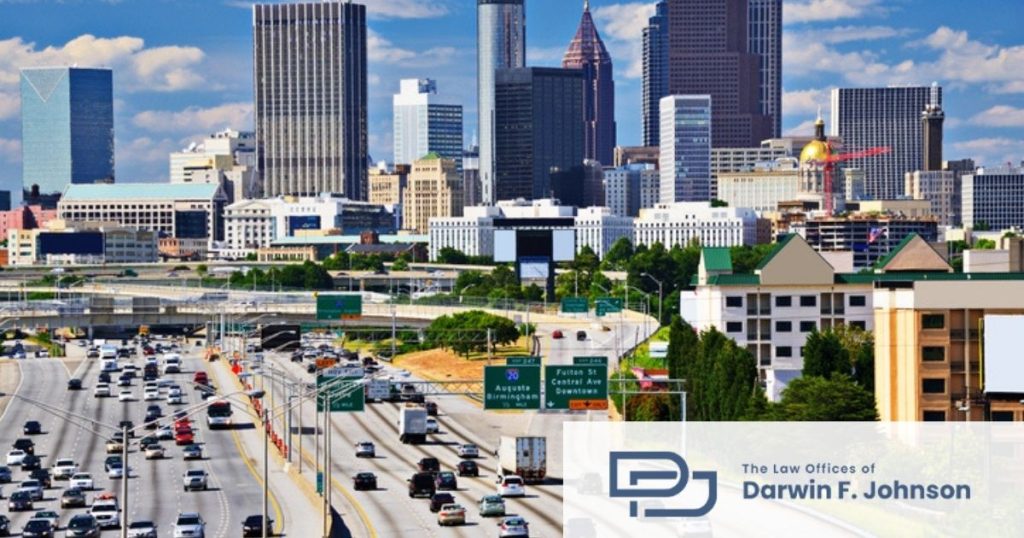A busy highway with multiple lanes runs through a cityscape with tall buildings. A logo for The Law Offices of Darwin F. Johnson appears in the lower right corner.