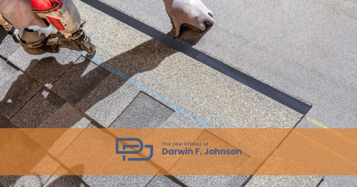 A worker installs asphalt shingles on a roof with a nail gun. The logo and name "The Law Offices of Darwin F. Johnson" appear across the bottom of the image.