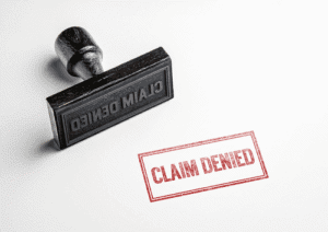 A black rubber stamp with the words "CLAIM DENIED" beside a red "CLAIM DENIED" stamp mark on a white background.